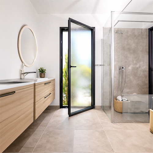 Porte-fenêtre aluminium à ouverture intérieure avec vitrage dépoli installée dans une salle de bain contemporaine lumineuse